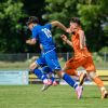 man in blue and orange jersey shirt running on green grass field during daytime
